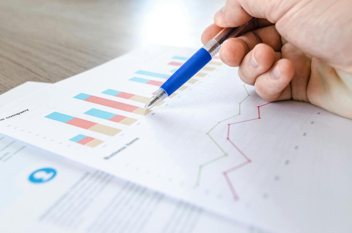 Hand holding pen pointing graphs